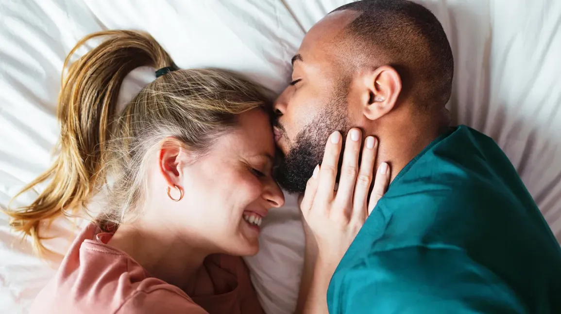 casal interracial se beijando na cama